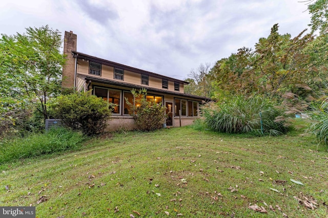 rear view of house featuring a sunroom and a lawn