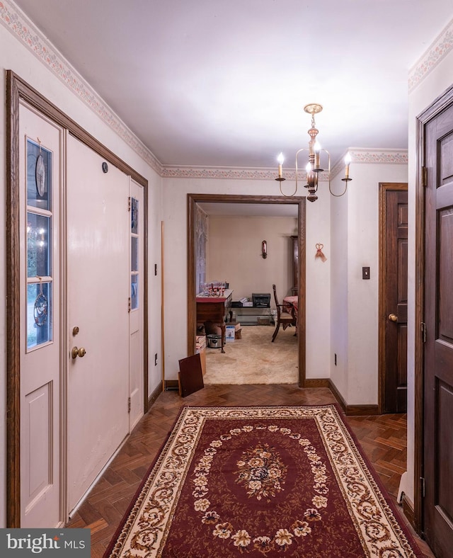 corridor with crown molding, a notable chandelier, and dark parquet floors