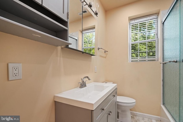 bathroom with vanity, toilet, and a shower with door