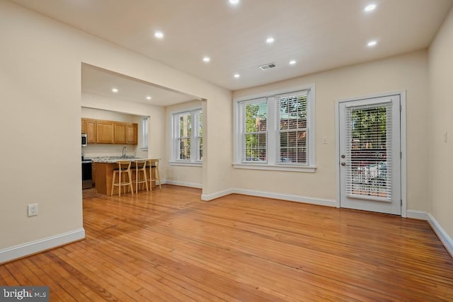 unfurnished living room with sink and light hardwood / wood-style flooring