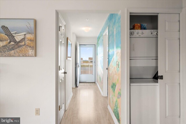 corridor with light hardwood / wood-style flooring and stacked washer and dryer