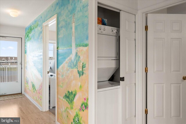 clothes washing area with stacked washer and clothes dryer and light hardwood / wood-style flooring