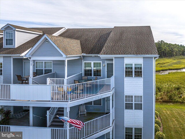 back of house with a deck and a lawn