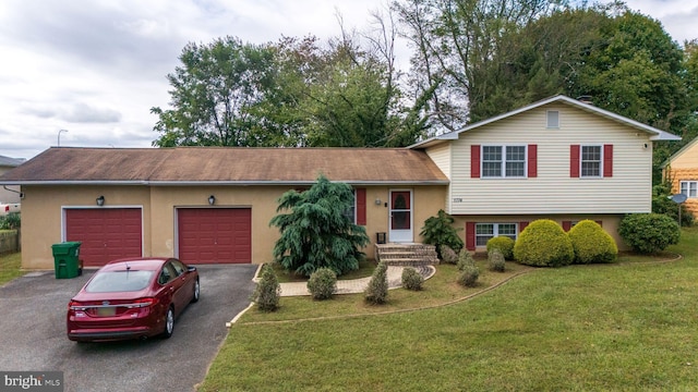 tri-level home with driveway, stucco siding, an attached garage, and a front lawn