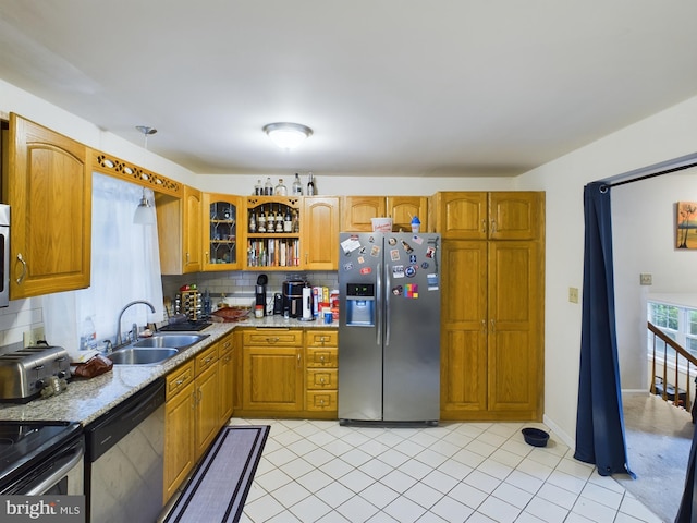 kitchen featuring brown cabinetry, tasteful backsplash, a sink, and stainless steel appliances