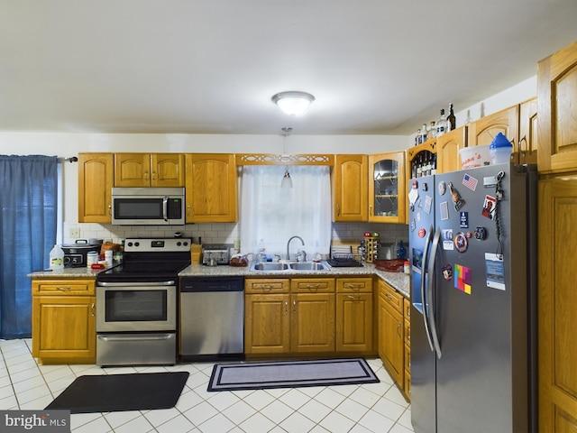 kitchen with appliances with stainless steel finishes, light tile patterned flooring, sink, and tasteful backsplash