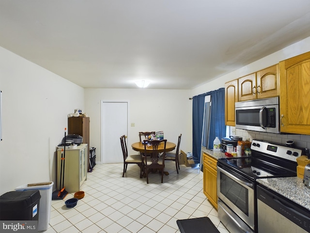 kitchen featuring stainless steel appliances, decorative backsplash, light stone counters, and light tile patterned floors