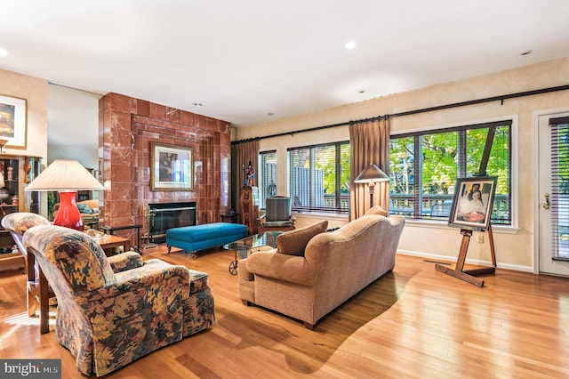 living area with baseboards, recessed lighting, wood finished floors, and a tiled fireplace