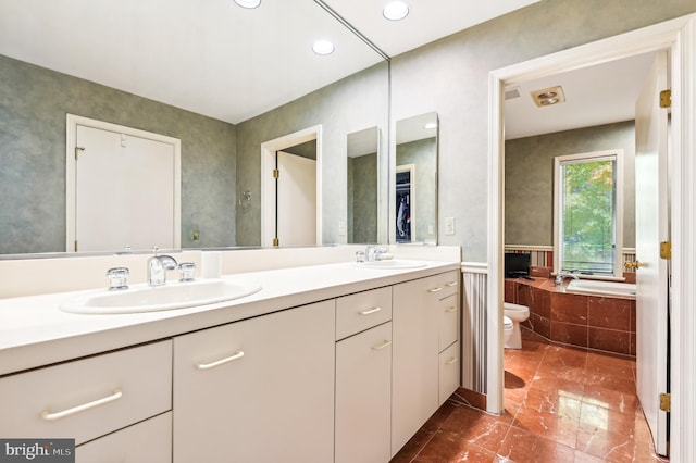 bathroom with vanity, a relaxing tiled tub, and toilet