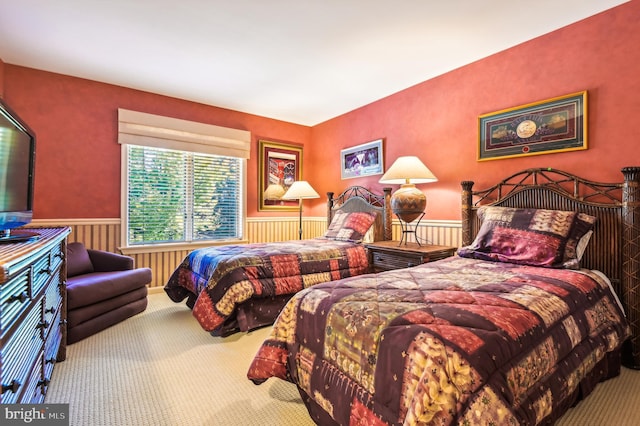 carpeted bedroom featuring a wainscoted wall