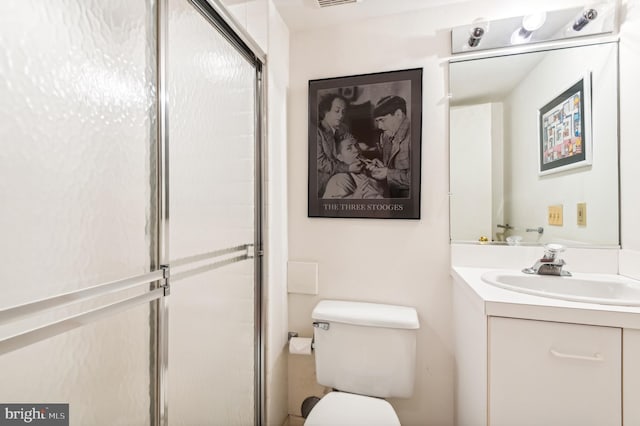 bathroom with toilet, vanity, and a shower with door