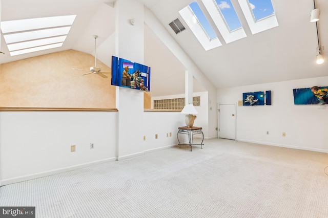 unfurnished living room featuring a skylight, light colored carpet, high vaulted ceiling, and ceiling fan