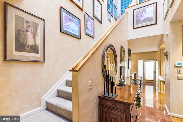 stairway featuring a towering ceiling