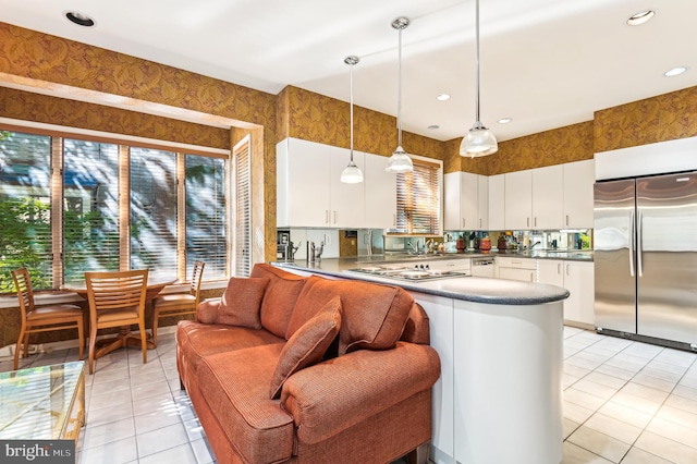 kitchen featuring kitchen peninsula, white cabinetry, stainless steel appliances, pendant lighting, and light tile patterned floors