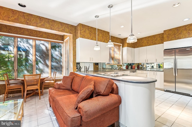 kitchen with white cabinetry, stainless steel appliances, light tile patterned flooring, and decorative light fixtures