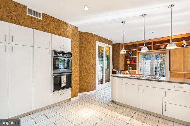 kitchen featuring decorative light fixtures, dobule oven black, white cabinets, stainless steel stovetop, and visible vents