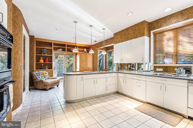 kitchen with white cabinetry, sink, kitchen peninsula, and hanging light fixtures