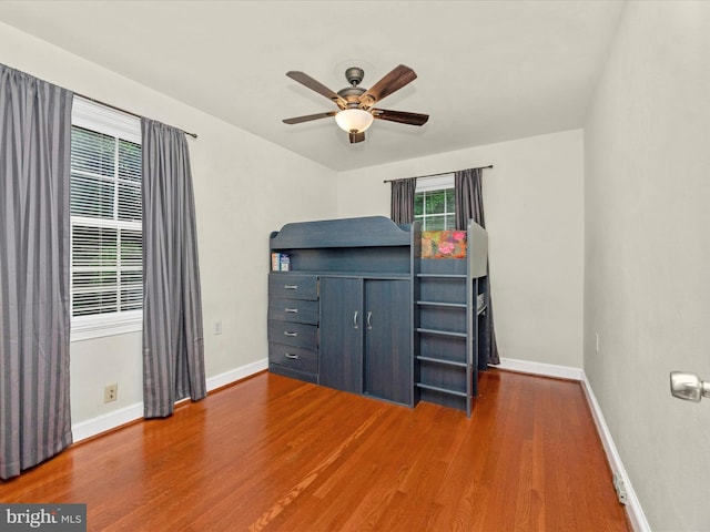 unfurnished bedroom with ceiling fan and dark wood-type flooring