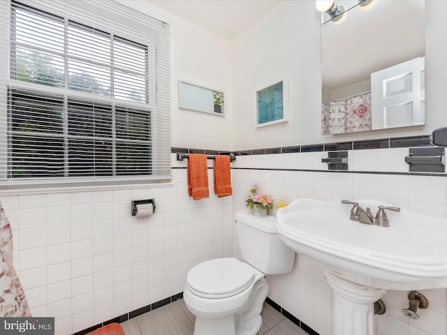 bathroom with tile walls, tile patterned flooring, a shower with curtain, and toilet