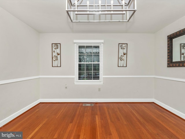 empty room with an inviting chandelier and hardwood / wood-style floors