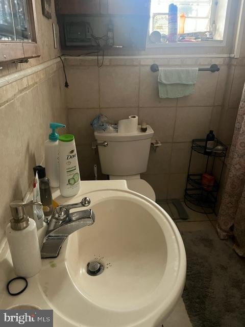 bathroom featuring tile walls, toilet, and sink