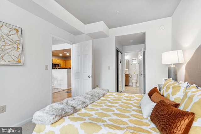 bedroom with ensuite bath and light colored carpet