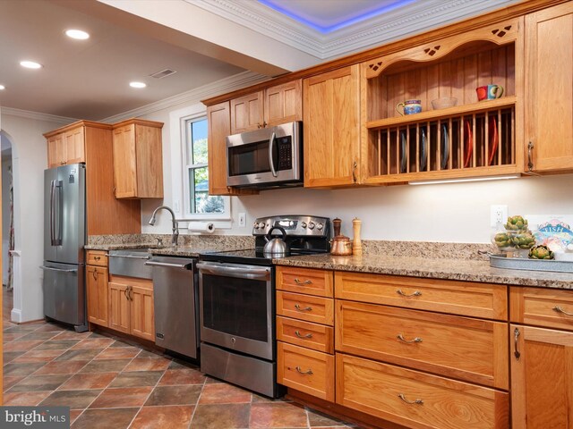 kitchen with crown molding, appliances with stainless steel finishes, sink, and light stone countertops