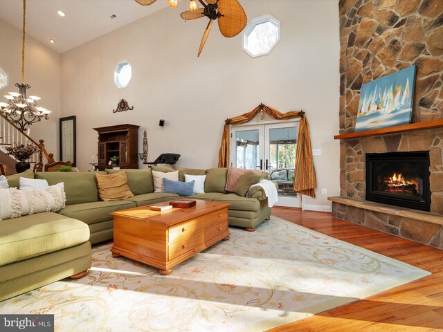 living room with a fireplace, ceiling fan with notable chandelier, high vaulted ceiling, and hardwood / wood-style floors