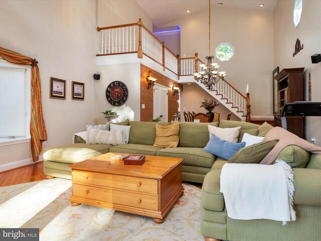 living room with hardwood / wood-style flooring, high vaulted ceiling, and a notable chandelier