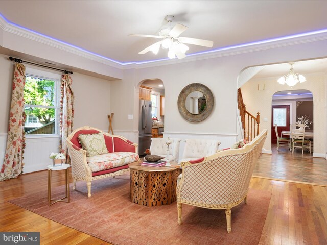 living room featuring ceiling fan with notable chandelier, crown molding, and hardwood / wood-style flooring