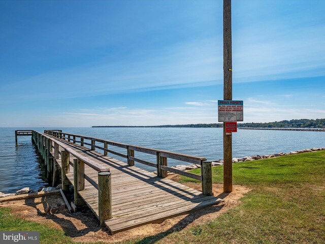 view of dock with a water view and a yard