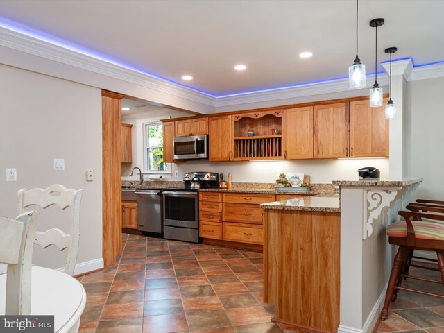 kitchen featuring light stone countertops, appliances with stainless steel finishes, crown molding, hanging light fixtures, and a breakfast bar