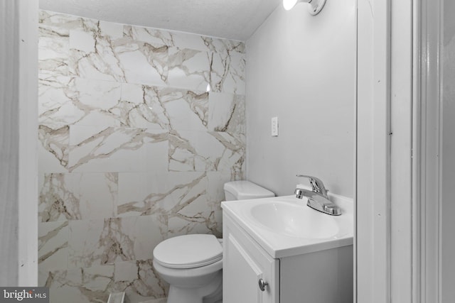 bathroom featuring toilet, a textured ceiling, and vanity