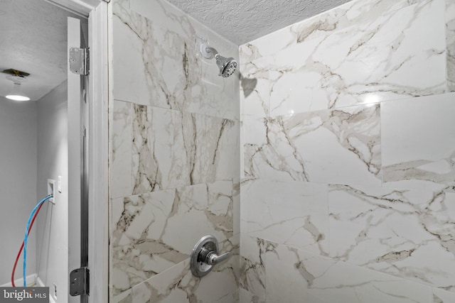 bathroom featuring a textured ceiling and a tile shower