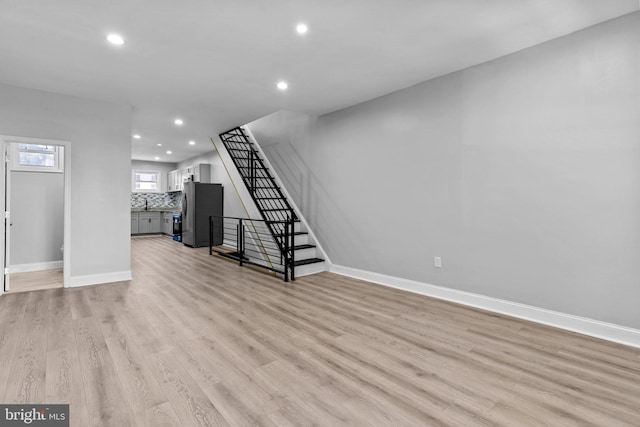 basement featuring light wood-type flooring and stainless steel refrigerator