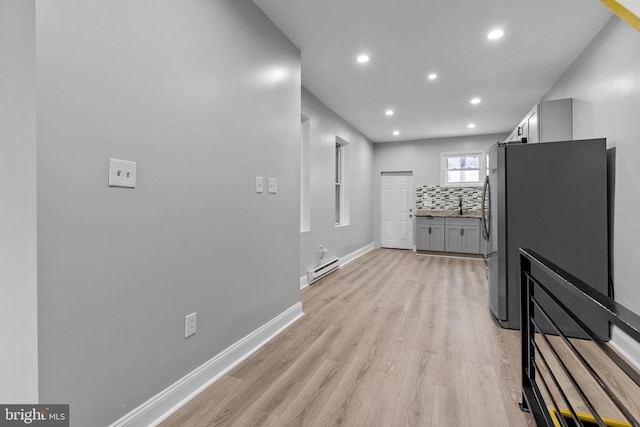 hallway featuring a baseboard heating unit, light hardwood / wood-style floors, and sink