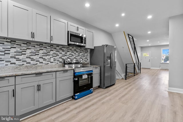 kitchen featuring gray cabinetry, tasteful backsplash, appliances with stainless steel finishes, and light hardwood / wood-style floors