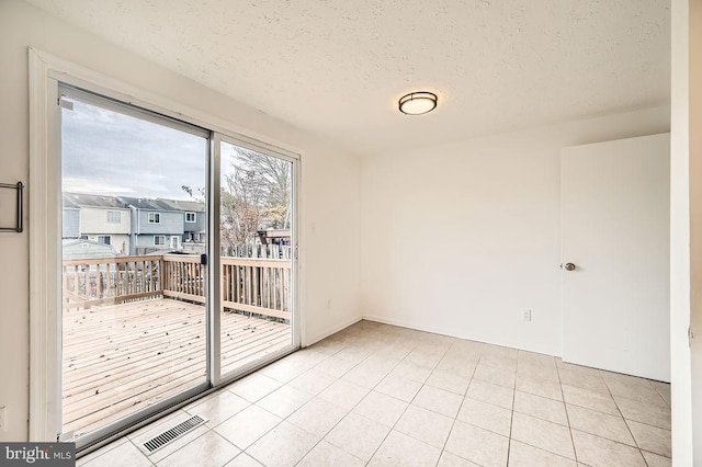 unfurnished room with light tile patterned floors and a textured ceiling