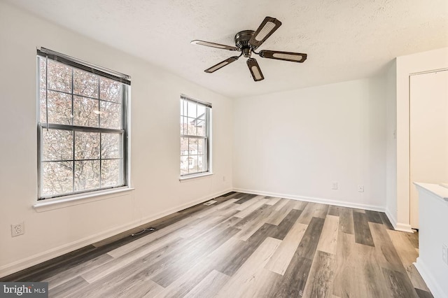 unfurnished room featuring hardwood / wood-style floors, ceiling fan, and a textured ceiling