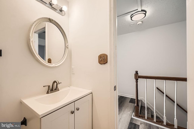 bathroom featuring hardwood / wood-style flooring, vanity, and a textured ceiling