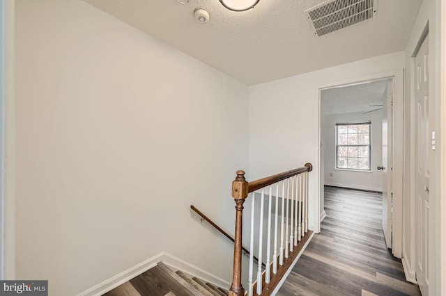 staircase featuring hardwood / wood-style floors and a textured ceiling