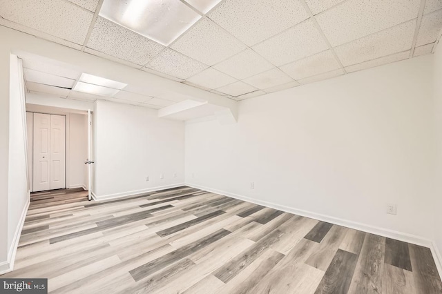 basement featuring a paneled ceiling and light hardwood / wood-style flooring