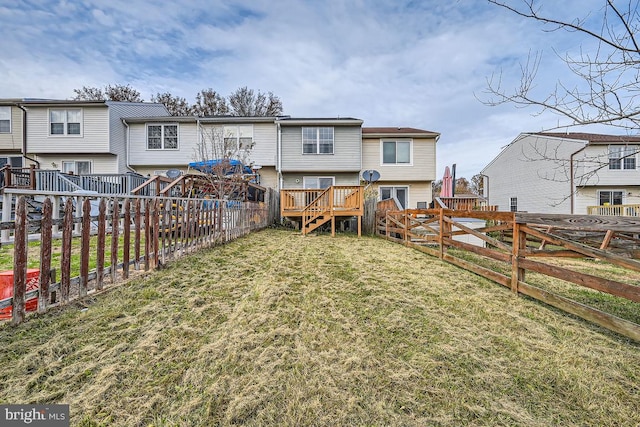 rear view of property featuring a wooden deck and a lawn