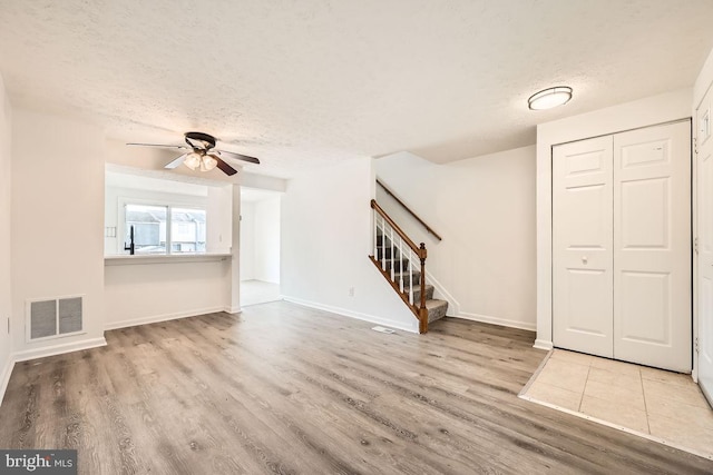 unfurnished living room featuring ceiling fan, light hardwood / wood-style flooring, and a textured ceiling