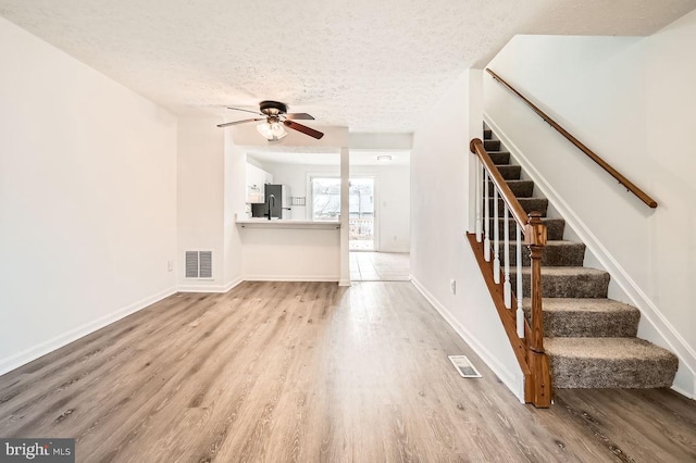 unfurnished living room featuring a textured ceiling, light hardwood / wood-style floors, and ceiling fan