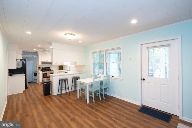 interior space featuring plenty of natural light, kitchen peninsula, white cabinets, and stainless steel range oven