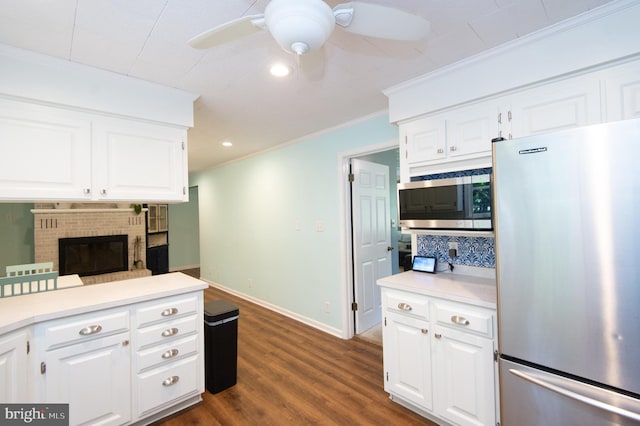 kitchen with white cabinets, appliances with stainless steel finishes, a fireplace, and ceiling fan