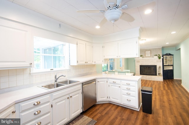 kitchen featuring a brick fireplace, white cabinetry, dark hardwood / wood-style floors, ceiling fan, and stainless steel dishwasher