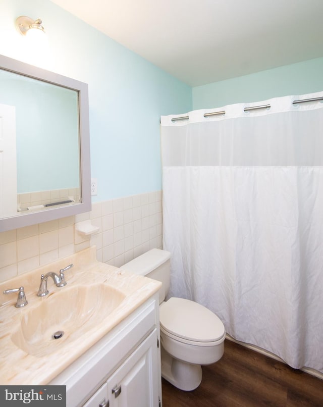 bathroom with toilet, vanity, wood-type flooring, decorative backsplash, and tile walls