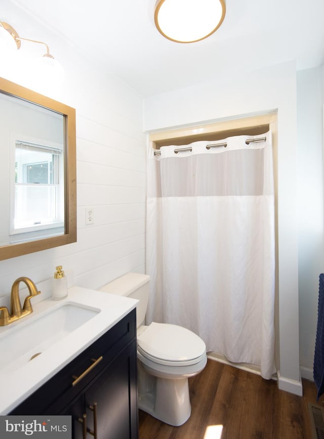 bathroom featuring toilet, vanity, curtained shower, wood walls, and wood-type flooring